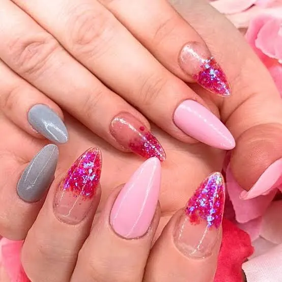 Close-up of pink and grey glittery almond-shaped manicured nails