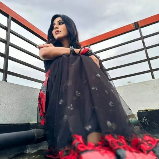 Sumona in a black and red saree on a rooftop during a photo session