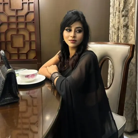 Sumona seated at a table during a beauty photo session