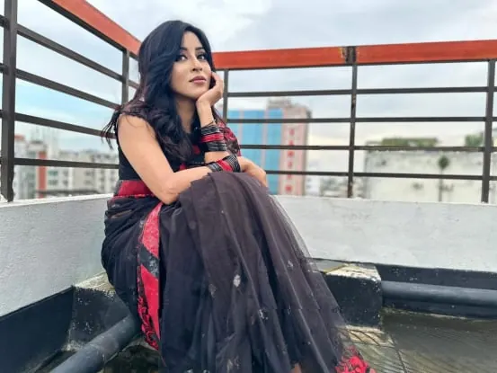 Sumona seated on a rooftop with city buildings behind her