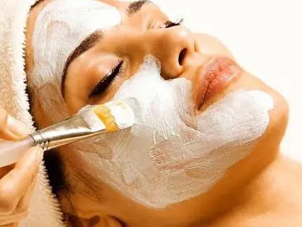 Cosmetic mask being applied to a client's face during a facial